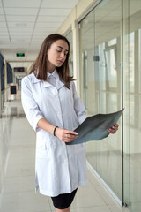 Fototapeta na wymiar Portrait of female intern nurse examining an x-ray patient in modern hospital