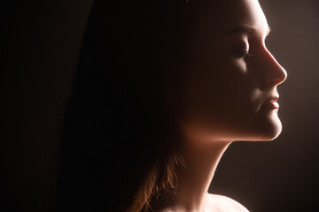 Fototapeta premium Peaceful woman. Enlightenment recreation. Profile portrait of tranquil lady with closed eyes isolated on dark background. Mindfulness relaxation. Subconscious contemplation.