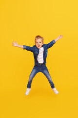 Fototapeta na wymiar Full length portrait of excited little child boy Jumping for joy isolated on yellow background.