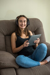 Obraz premium Young pretty slim woman looking at her tablet lying on the comfy couch