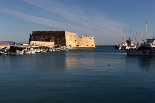 Ancient, urban, medieval, marine, Venetian fortress Kules (island Crete, city Heraklion, Greece) and fishing boats on a sunny morning.