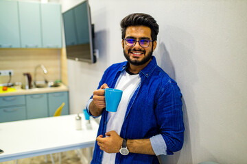 arabian man in casual dress holning a blue cup and looking dreamly