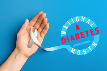 Female hand with awareness ribbon and text NATIONAL DIABETES AWARENESS MONTH on blue background