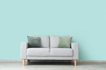 Stylish sofa near color wall in room