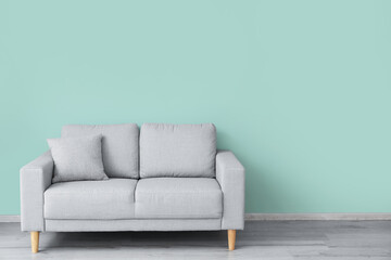 Stylish sofa near color wall in room