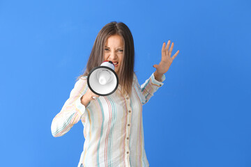 Fototapeta premium Angry young woman with megaphone on color background