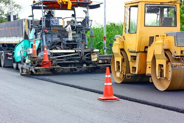 Naklejka premium asphalt paver machine making asphalt road with road roller