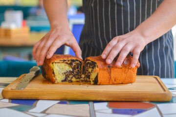 Close-up of a chef holding bread, cutting bread. Professional chef cook cut loaf of bread outside. Restaurant concept.