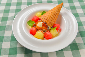 Refreshing melon ice cream with a cone in a white plate. Delicious summer dessert. Cold ice cream fruit sorbet.