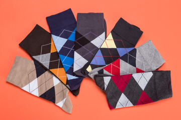 seven socks with color patterns of rhombuses lined in a semicircle on orange background