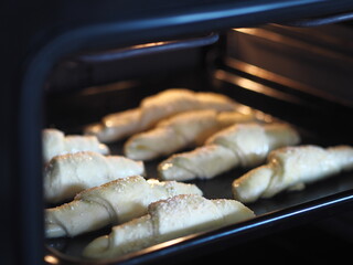 Croissants, sprinkled with sesame and sugar on a baking sheet in the kitchen oven, are ready to be baked.Homemade cake.