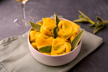 Tortelloni with aromatic sage, ricotta and spinach. Italian egg paste and white wine. Traditional Bologna cuisine, Emilia Romagna region. Close-up. High quality photo