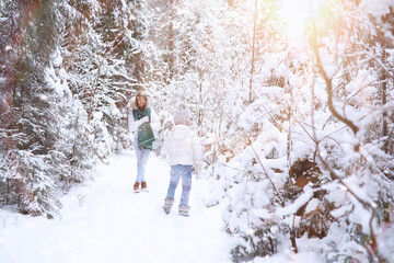 Young family for a walk. Mom and daughter are walking in a winter park.