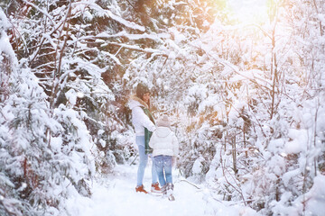 Young family for a walk. Mom and daughter are walking in a winter park.