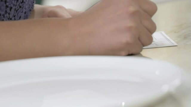 A woman is writing on a white piece of paper that sits on a marble table.