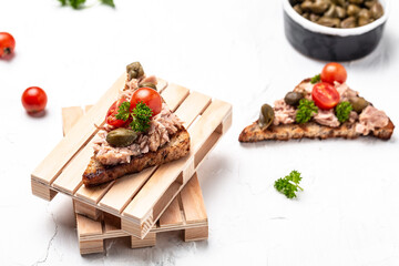 tuna crostini sandwiches. Italian bruschetta sandwiches with canned tuna, tomatoes and capers on the whole grain bread, Top view