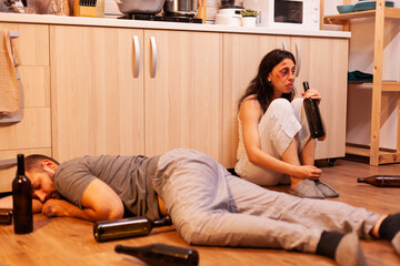 Abused wife drinking alcohol near drunk and abussive husband in kitchen. Alcoholic aggressive man...