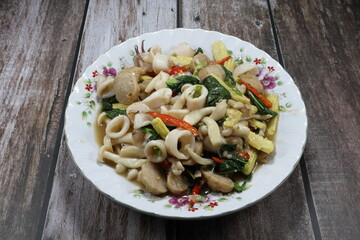 Fried and stirred spicy mixed fresh shrimp ball, cutting squid, sliced baby corn, chilly and basil on the plate. Famous traditional hot and spicy seafood menu in Asia restaurant. 