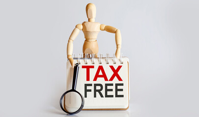 Wooden man shows with a hand to white notepad with text TAX FREE