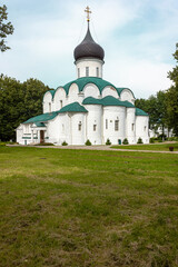 Fototapeta na wymiar White Orthodox church with a black dome and a green roof against a background of blue sky and clouds. Russia, the city of Alexandrov.