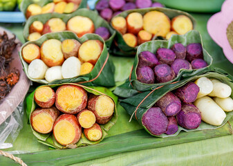 Sweet potatoes steamed and wrapped in fresh banana leaves at street food market in Thailand