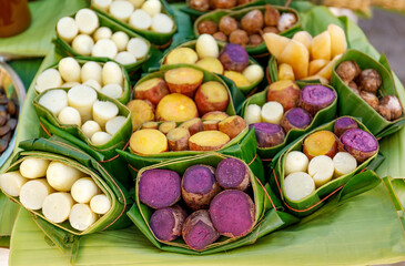 Sweet potatoes steamed and wrapped in fresh banana leaves at street food market in Thailand