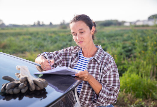 Portrait of female farmer signing documents near car outside