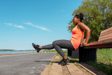 fitness, sport and healthy lifestyle concept - young african american woman exercising with bench at seaside