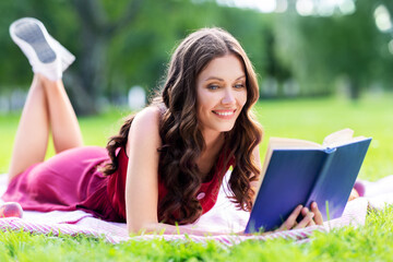 leisure and people concept - happy smiling young woman reading book at summer park