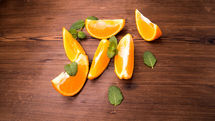 Mandarin slices in mint leaves on an old dark wooden table, close-up with space for text