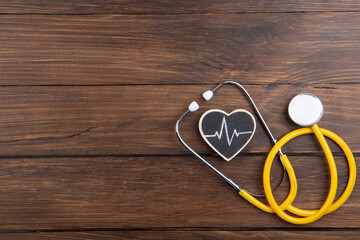 Workplace of a doctor. Stethoscope and little heart on wooden desk background