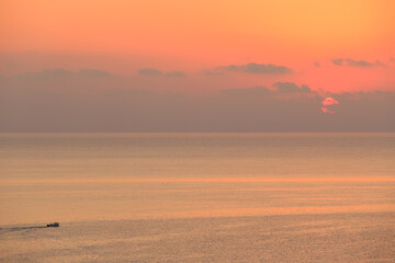 Beautiful sunset or dawn over the sea with a small boat and great sunshine 