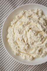 Tasty Ricotta Cheese in a white bowl, top view. Overhead, from above, flat lay. Close-up.