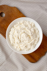Tasty Ricotta Cheese in a white bowl, top view. Overhead, from above, flat lay.