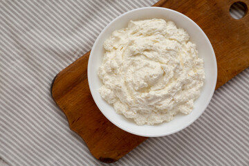 Tasty Ricotta Cheese in a white bowl, top view. Overhead, from above, flat lay. Copy space.