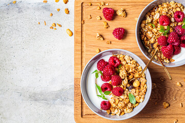 Muesli with raspberries and yoghurt in gray bowl, top view, copy space, Healthy food concept.