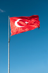 Turkish national flag waving in blue sky.