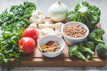 Cooking background of fresh vegetables, spices and beans. Raw ingredients for cooking vegetarian curry with vegetables and chickpeas on a wooden board.