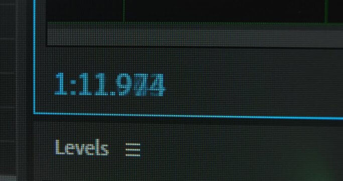 Timecode blue digits change while film editor processes video sequence in program on black monitor macro view