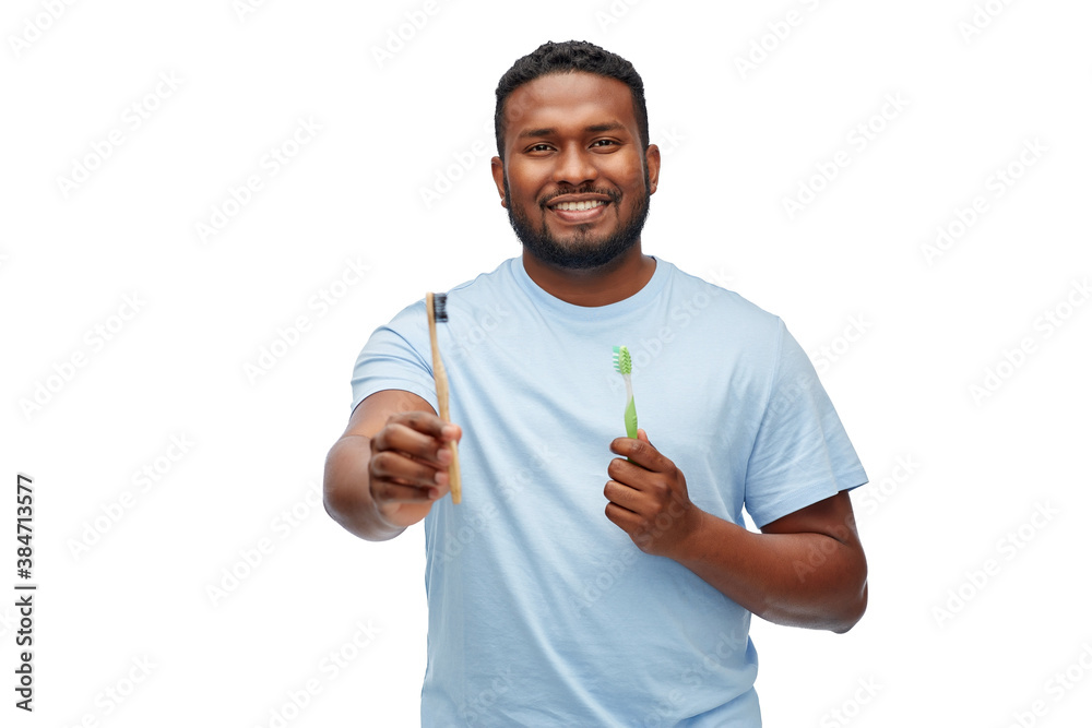 Wall mural health care, dental hygiene and people concept - smiling african american young man with wooden and plastic toothbrushes over white background