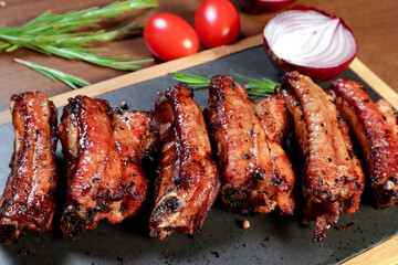 Grilled pork ribs with vegetables and spices on a wooden board. European cuisine.