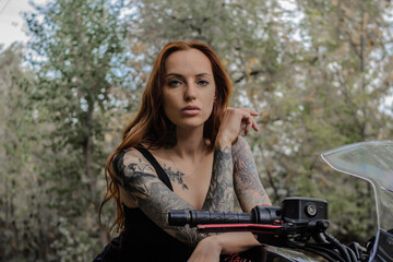 Red-haired tattoo model in the woods