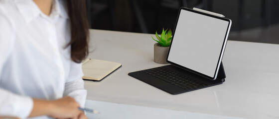 Female worker sitting at worktable with clipping path tablet and notebook