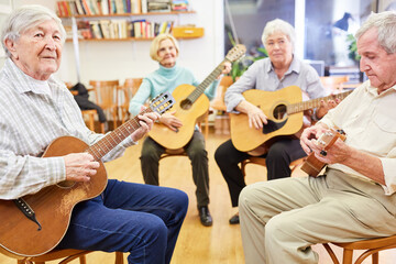 Gruppe Senioren lernt Gitarre spielen zusammen in einem Gitarrenkurs im Altersheim