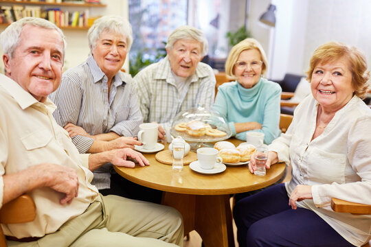 Gruppe Senioren sitzt gemeinsam am Kaffeetisch im Aufenthaltsraum im Seniorenheim