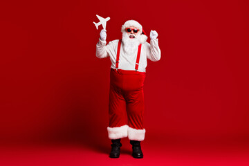Fototapeta na wymiar Full length body size view of his he attractive cheerful lucky glad fat Santa holding in hands paper plane having fun isolated bright vivid shine vibrant red burgundy maroon color background