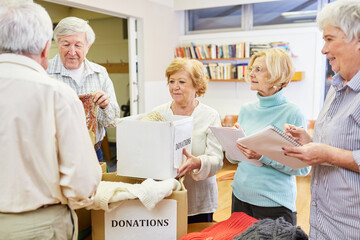 Senioren als freiwillige Helfer mit Kleiderspenden bei einer Spendensammlung - obrazy, fototapety, plakaty