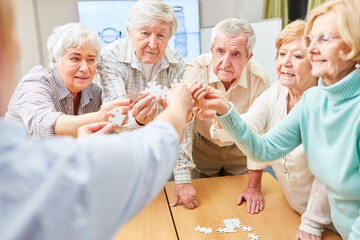 Gruppe dementer Senioren trainiert das Gedächtnis beim Puzzle spielen im Altenheim