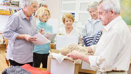 Senioren als freiwillige Helfer im Ehrenamt sortieren Kleiderspende