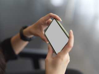 Female hands holding clipping path horizontal smartphone in blurred background